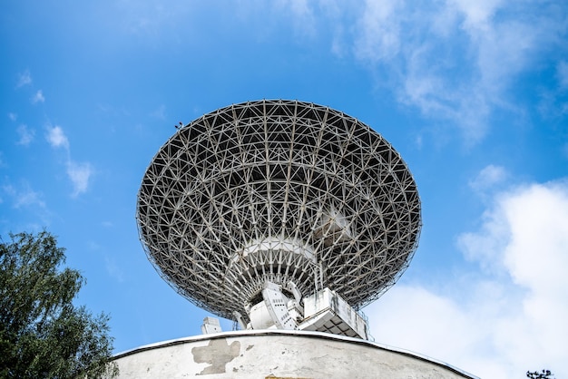 Duża antena na szczycie budynku z niebieskim niebem w tle.