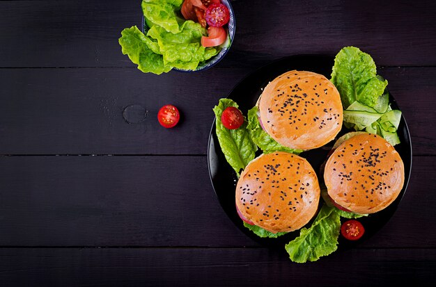 Duża kanapka - burger hamburgerowy z wołowiną, pomidorem, serem i sałatą. Widok z góry. Leżał płasko