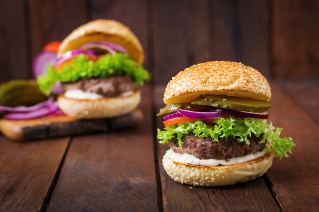 Duża Kanapka - Hamburger Burger Z Wołowiną, Marynatami, Pomidorem I Sosem Tatarskim Na Drewnianym Tle.