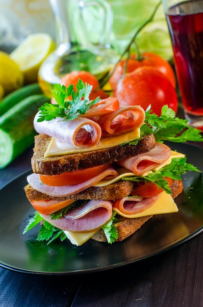 Zdjęcie duża kanapka z kiełbasą i serem, ogórkiem i pomidorem