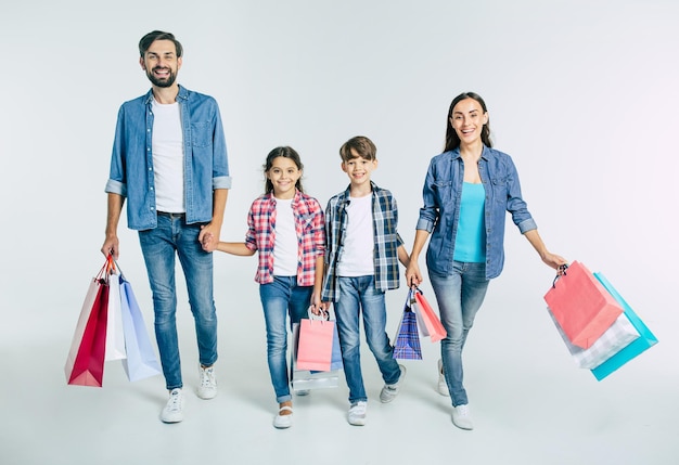 Duża piękna szczęśliwa i podekscytowana rodzina spacerująca razem po zakupach w centrum handlowym z zakupami w rękach na białym tle