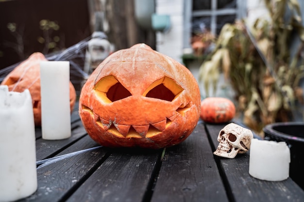 Duża pomarańczowa dynia na halloween jackolantern z przerażającymi rzeźbionymi oczami w ustachBez świeczkikull na starym drewnianym stole w pobliżu stodołyDIY homestreet decorationrozrywka dla dzieciatmosfera horroru