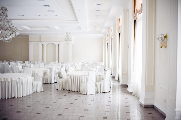 Duża sala balowa ze stołami i krzesłami na przyjęcie weselne.
