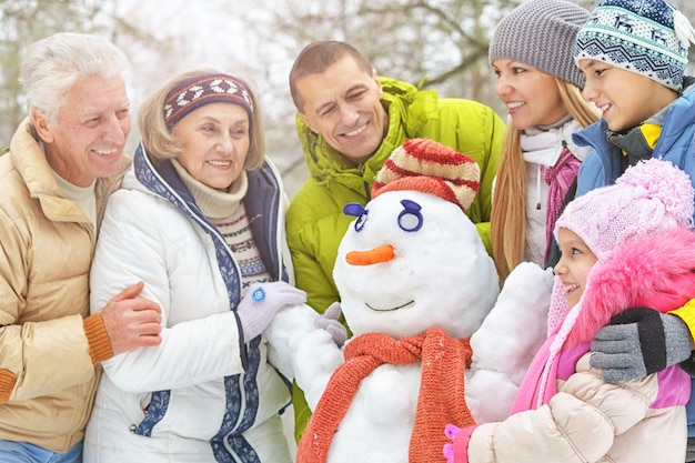 Duża szczęśliwa rodzina bawi się w zimowym parku pokrytym śniegiem