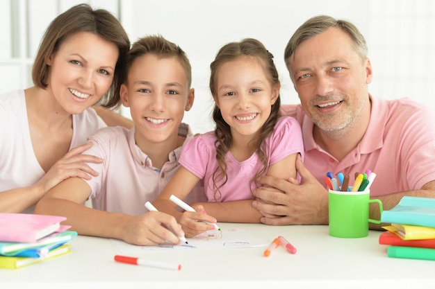 Duża szczęśliwa rodzina odrabiająca pracę domową w domu