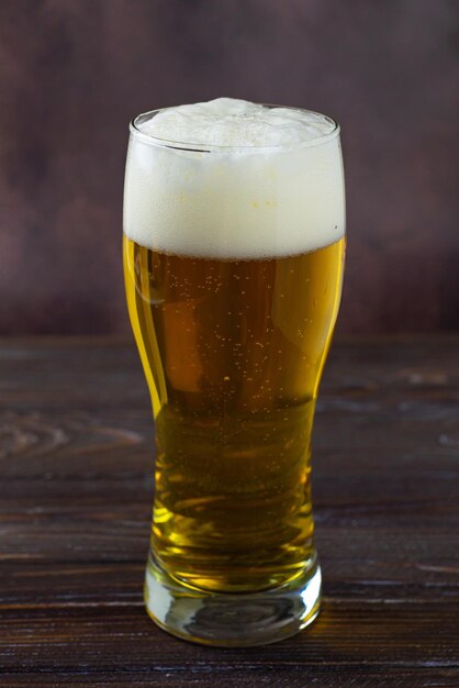 duża szklanka zimnego jasnego piwa z pianką na ciemnym tle Dzień Świętego Patryka