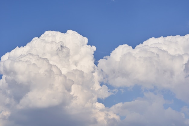 Duże białe puszyste chmury cumulonimbus unoszące się na błękitnym niebie w jasny słoneczny dzień