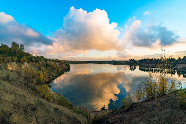 Zdjęcie duże chmury o zachodzie słońca nad jeziorem jesienią.