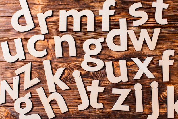 Zdjęcie duże litery alfabetu są chaotycznie rozrzucone na drewnianym tle. koncepcja edukacji