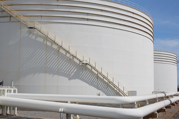 Duże zbiorniki przemysłowe na olej z przejściem w górę iw dół po metalowych schodkach zbiornika do przechowywania oleju z boku pojemnika na olej przemysłowy.