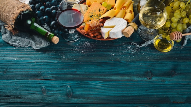 Duży asortyment serów wino miód orzechy i przyprawy na niebieskim drewnianym stole Widok z góry Wolne miejsce na tekst