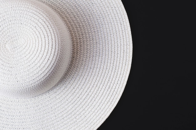Duży biały plażowy kobiecy kapelusz na czarnym tle. Pojęcie wakacji