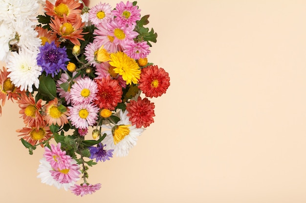 Duży bukiet kolorowych kwiatów różnych na beżowym tle.
