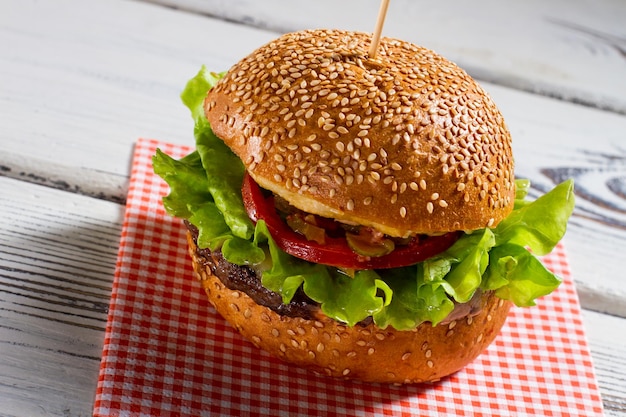 Duży burger na serwetce Hamburger z bułkami sezamowymi Świeży burger wołowy na białym stole Nowe danie warte skosztowania