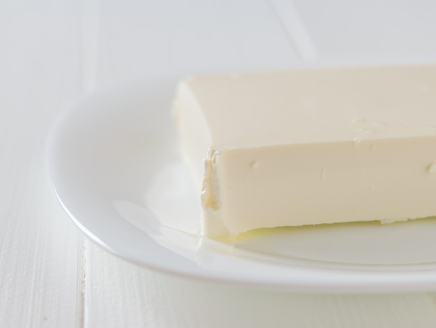 Duży kawałek sera na białym talerzu na białym stole