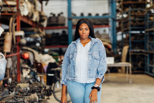 Duży model african american kobieta. Stare części samochodowe do maszyn w magazynach. Auto mechanik samochodowy serwis, naprawa i koncepcja konserwacji. używane mobilne części zamienne do samochodów-samochodów