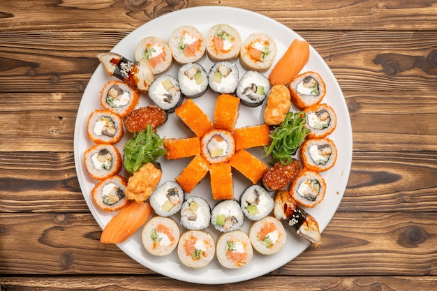 Duży, piękny zestaw sushi z bułkami maki, nigiri i gunkanami na białym okrągłym talerzu ceramicznym