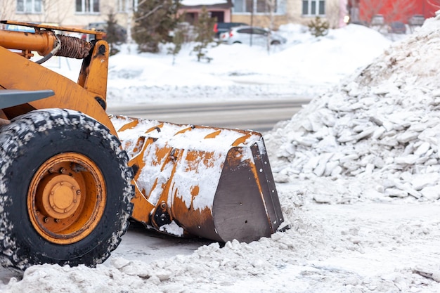 Duży pomarańczowy traktor odśnieża drogi Sprzątanie i czyszczenie dróg w mieście od