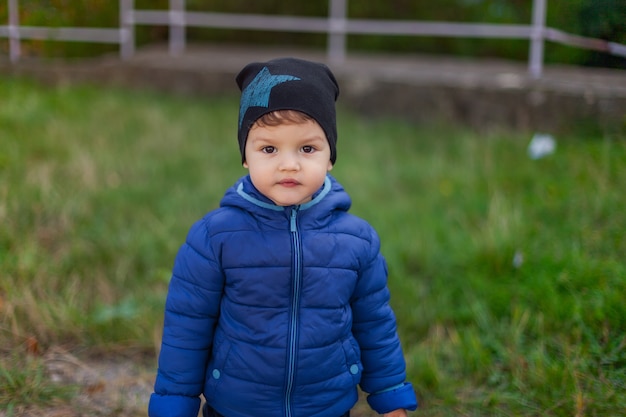 Duży portret dziecka na ulicy. Jesień, poza sezonem, chłopiec w kurtce i kapeluszu. styl życia.