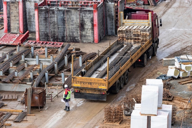 Duży samochód ciężarowy dostarcza materiał na plac budowy Dostawa okuć metalowych do budowy monolitycznego domu żelbetowego Odbiór materiałów budowlanych