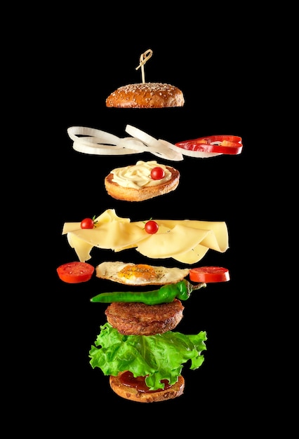 Duży smaczny burger z kotletem mięsnym, serem, jajkiem sadzonym, pomidorami, kawałkami ogórka i zieloną sałatą, fast food levitatesba