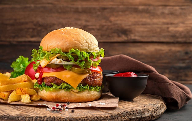 Duży soczysty burger z mięsem, serem i warzywami na brązowym tle. Widok z boku, zbliżenie. Fast food.