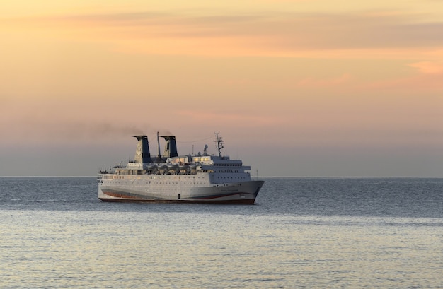Duży statek wypływa do morza o świcie, różowe złote niebo, miejsce na tekst. Rosja, Krym, 2019