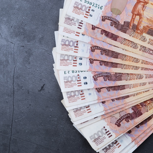 Duży stos banknotów rosyjskich pieniędzy z pięciu tysięcy rubli leżącego wentylatora na szary cement.
