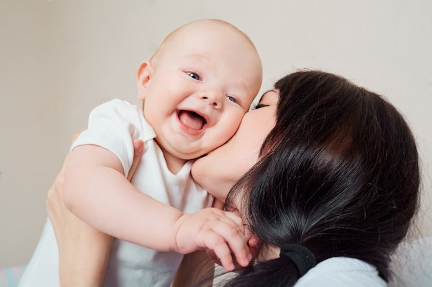 Duży uśmiech maluch mama przytula dziecko dziecko śmiejąc się w ramionach matki dużo śmiejąc się z koncepcji szczęśliwej rodziny