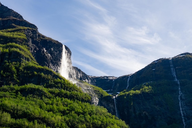 Duży wodospad, który wznosi się w górach otoczony zielonymi drzewami w Norwegii