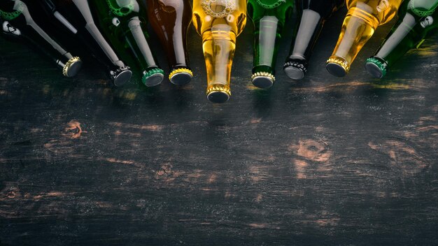 Duży wybór butelek piwa Na czarnym drewnianym stole Wolne miejsce na tekst Widok z góry