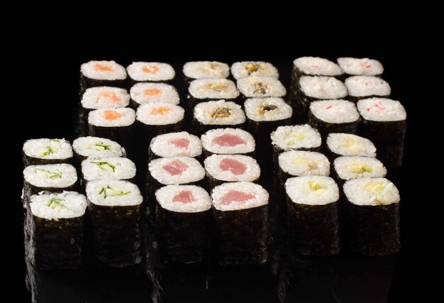Duży zestaw sushi na czarnym tle.Ð tradycyjne danie kuchni azjatyckiej.