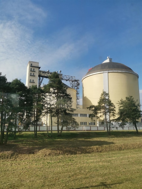 Duży żółty silos z czarnym dachem stoi przed polem.