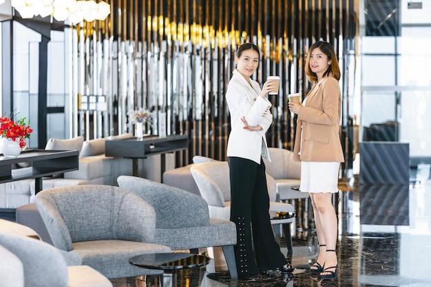 Dwa azjatykciego bizneswomanu opowiada podczas kawowej przerwy w nowożytnym biurze