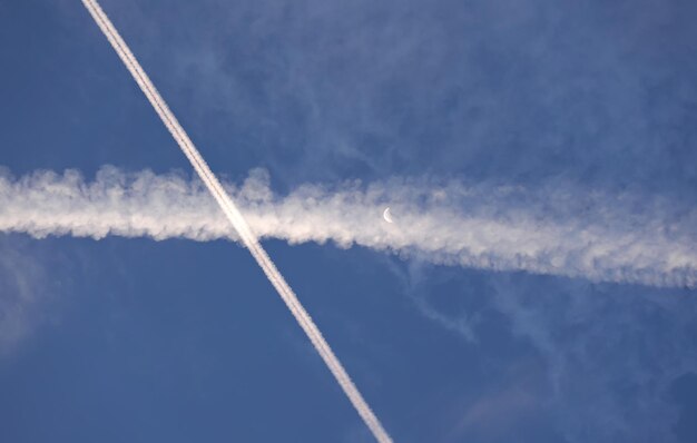 Dwa białe ślady z samolotów komercyjnych, biały księżyc w pobliżu - koncepcja teorii spiskowej chemtrails