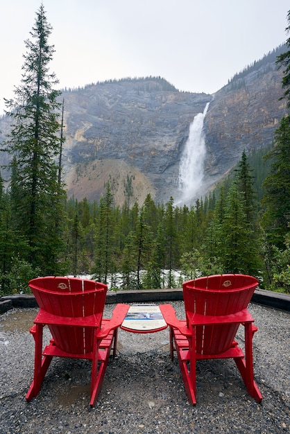 Dwa czerwone krzesła na dole Takakkaw spadają w deszczowy dzień