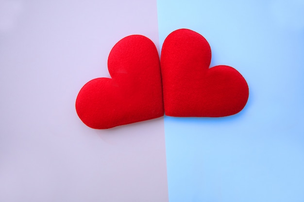 Dwa czerwone serca wykonane z flaneli układane są na różowo-niebiesko