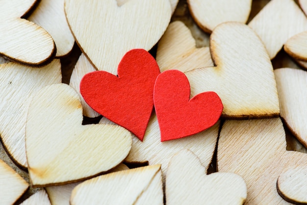 Dwa czerwonego serca z drewnianymi sercami na drewnianym tle.