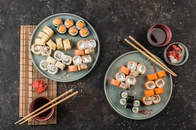 Dwa Duże Zestawy Z Roladami Sushi Serwowane Przez Szefa Kuchni Na Ciemnym Tle. Widok Z Góry Z Miejscem Na Kopię. Jedzenie W Restauracji. Leżał Na Płasko