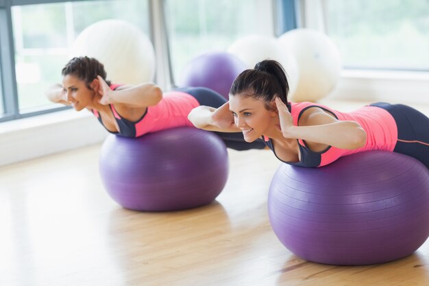 Dwa dysponowanej kobiety ćwiczy na sprawności fizycznych piłkach w gym