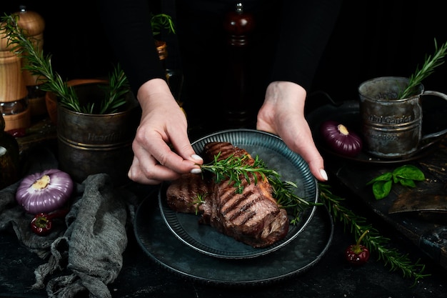 Dwa grillowany stek wołowy ribeye na talerzu w rękach szefa kuchni Baner żywności na czarnym tle