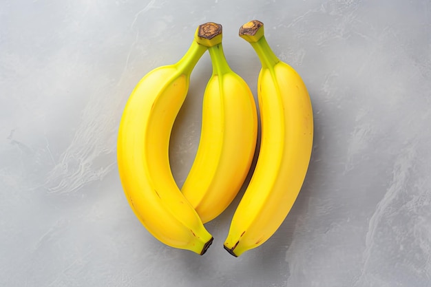 Zdjęcie dwa jasne żółte banany są umieszczone na szarej powierzchni tworząc minimalistyczny płaski układ tych bananów