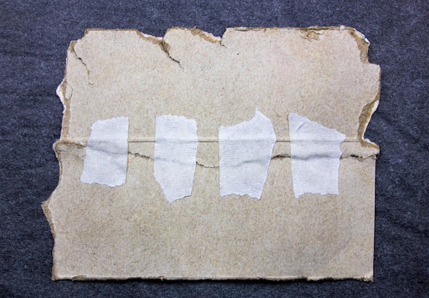 Dwa kawałki starej podartej tektury sklejone białą taśmą papierową Stary papier zniszczony przez tekturę Stary karton sklejony paskiem taśmy klejącej