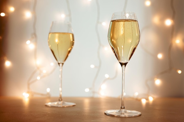 Dwa kieliszki do szampana lub wina musującego z kieliszkiem w bożonarodzeniowej lub noworocznej atmosferze, w tle świeci bokeh