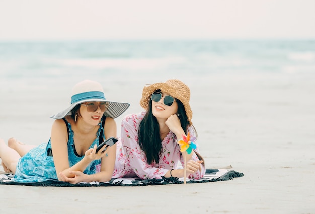 Dwa kobiety cieszy się plażowy relaksować radosny w lecie tropikalną błękitne wody. Model w podróży na sobie kapelusz plażowy.