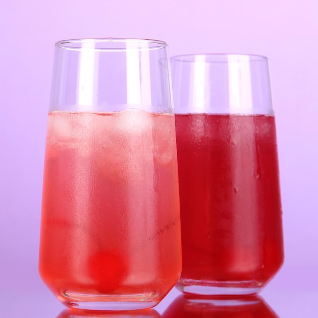 Zdjęcie dwa koktajle wiśniowe z lodem na fioletowym tle