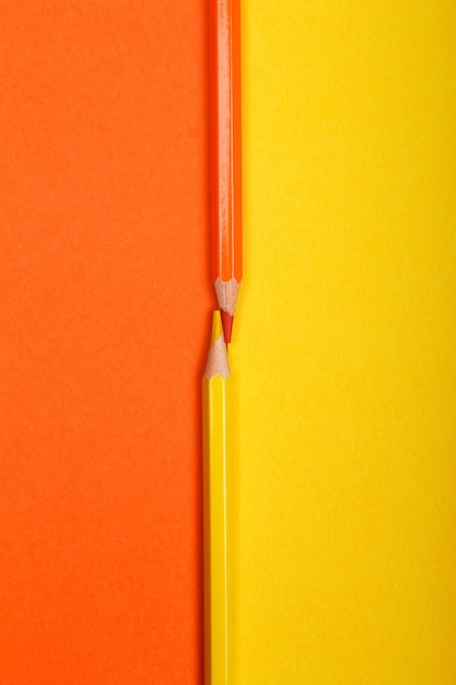 Dwa kolorowe kredki na białym tle na dwóch różnych kolorowych dokumentów w tle
