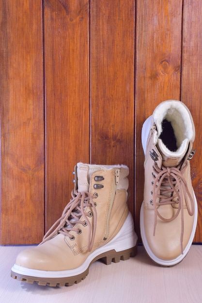 Dwa lekkie buty zimowe lub jesienne na brązowym drewnianym tle. Właściwy jest w pozycji pionowej.