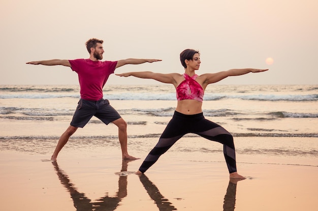 Dwa młody mężczyzna i piękna kobieta na plaży razem robi ćwiczenia jogi fitness. Element Acroyoga dla siły i równowagi podczas sea octan goa india sunset