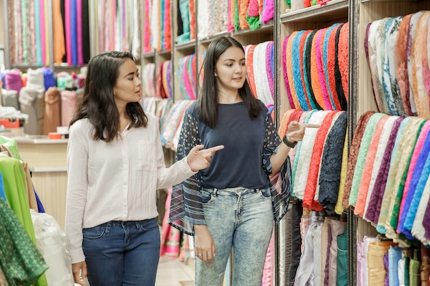 Dwa młodych kobiet shoppic w sklepie tkaniny